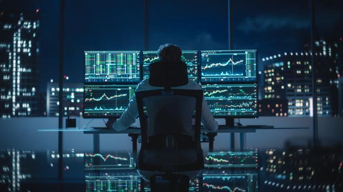 Un trader di criptovalute seduto alla sua scrivania”